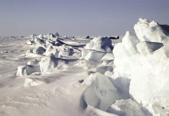 broken arctic sea ice floating on dark ocean water