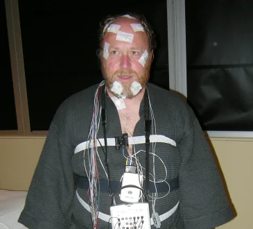 A volunteer wired with sensors during a sleep study in a laboratory